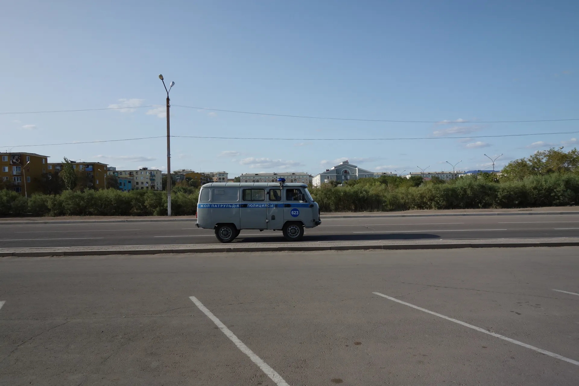 A UAZ van parked alone on an empty car park under a pale sky.