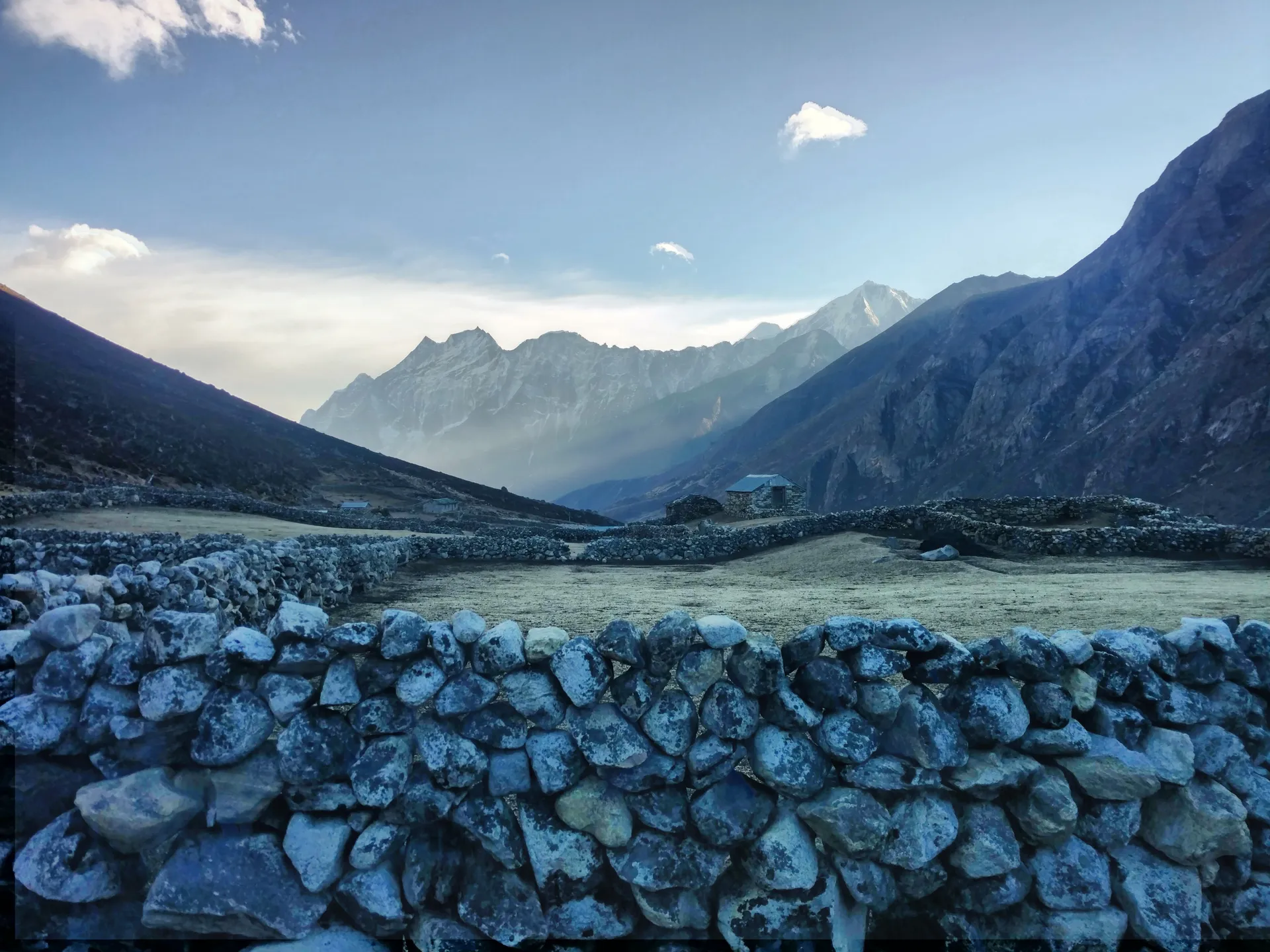 Dry stone walls in a wide Himalayan valley under a clear sky.