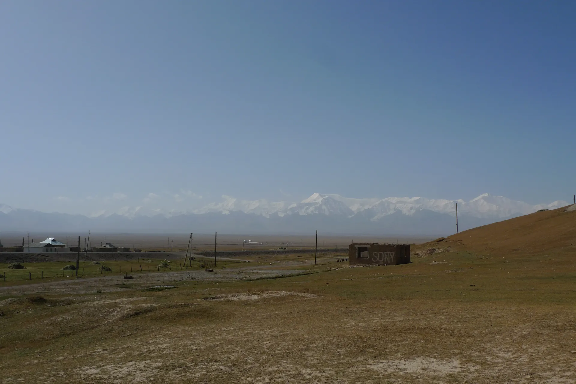 Dry steppe stretching towards a faint line of snowy mountains.