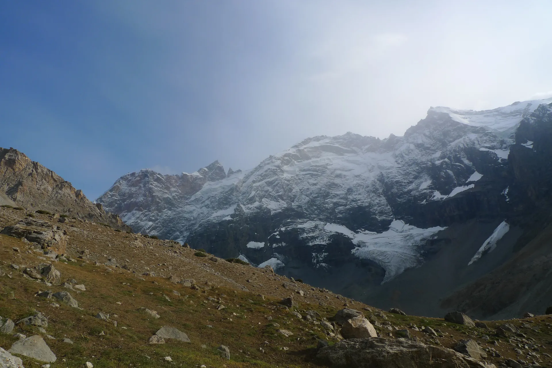 Fresh snow on the ridges above a brown autumn valley.