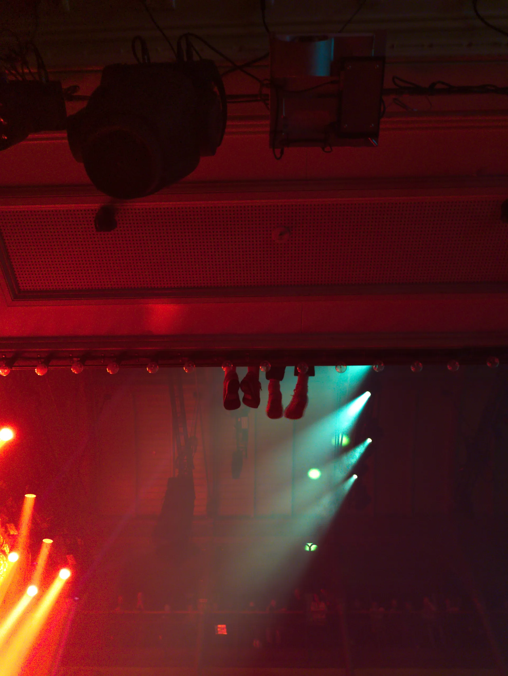 Red and green stage lights cutting through a dark concert hall.