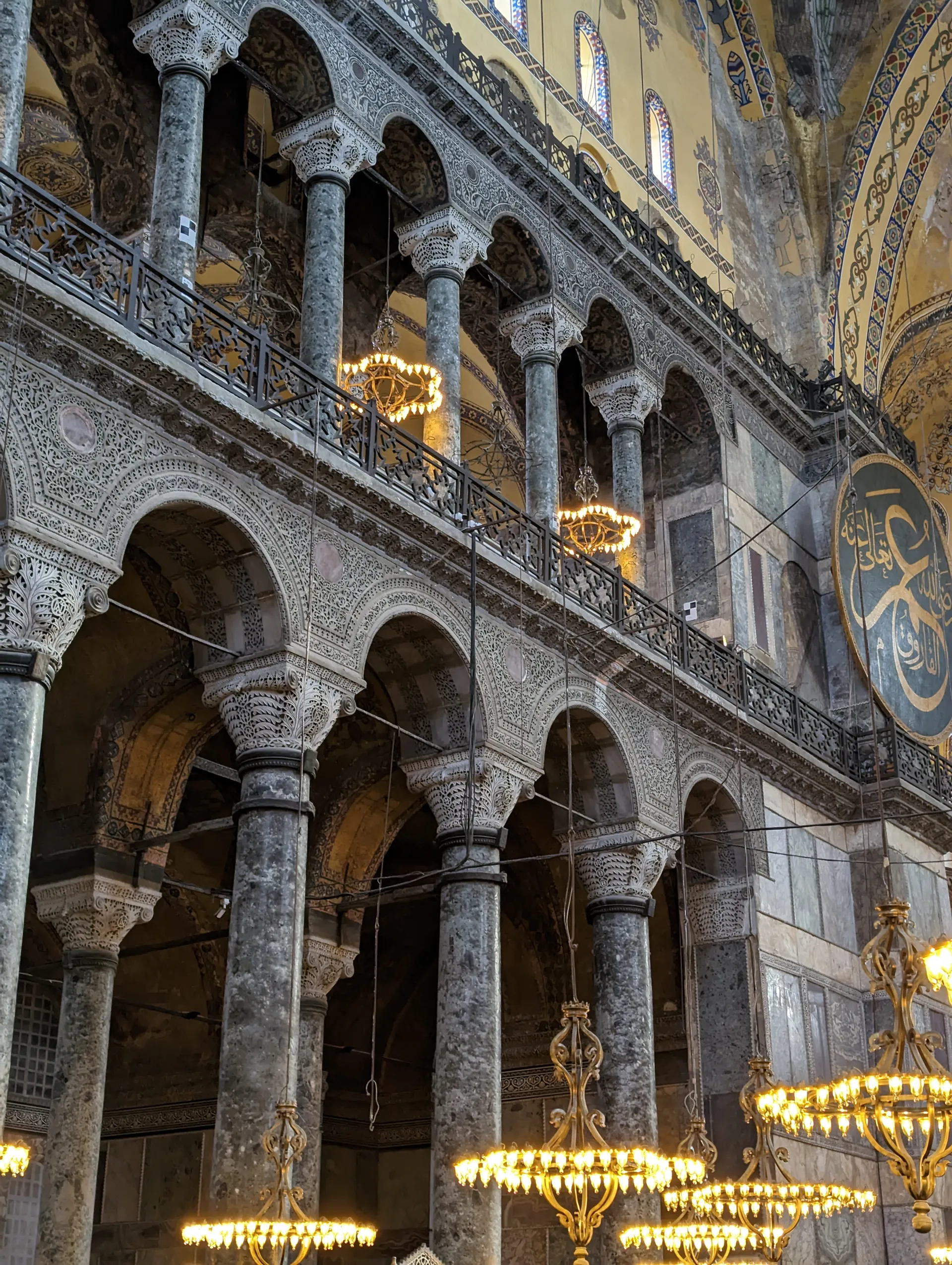 Stacked marble arcades and chandeliers inside a Byzantine hall.