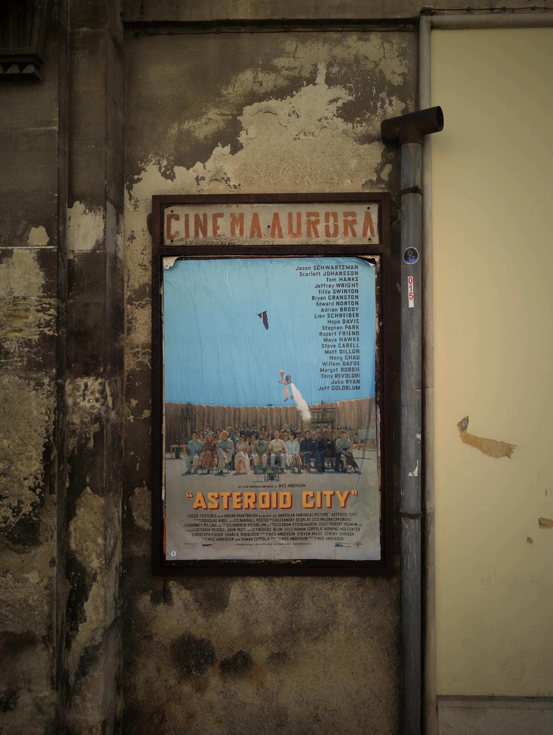 An Asteroid City poster on a weathered cinema wall.