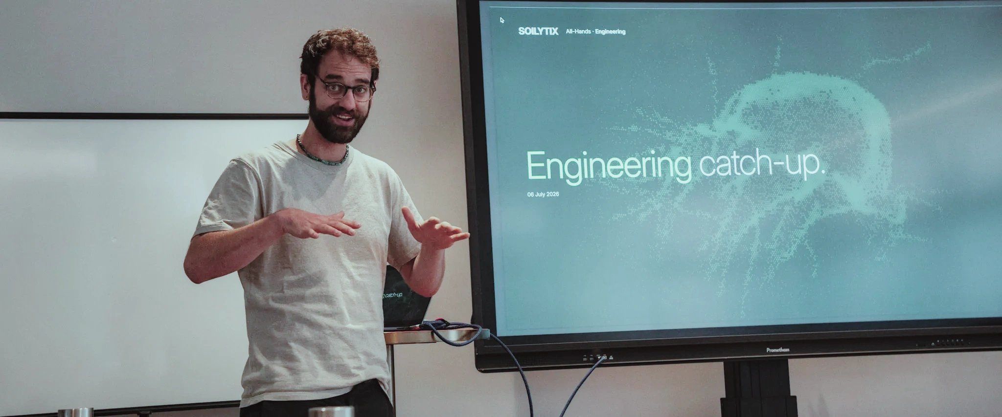 Maurice presenting the Soilytix engineering catch-up at the July 2026 all-hands in Hamburg, gesturing beside a screen reading “Engineering catch-up.”